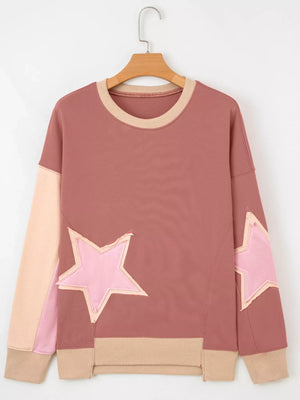 Dusty pink sweatshirt with contrast star patches and exposed seams.