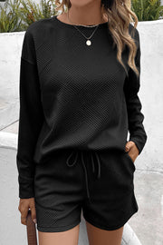 Black textured geometric loungewear set with crewneck sweatshirt and drawstring shorts.