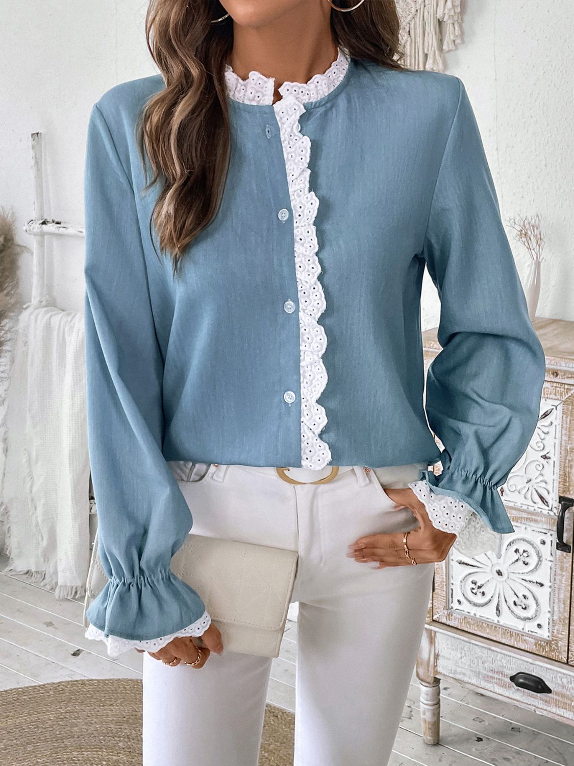 Light blue buttoned blouse with lace trim on neckline and cuffs, long sleeves.