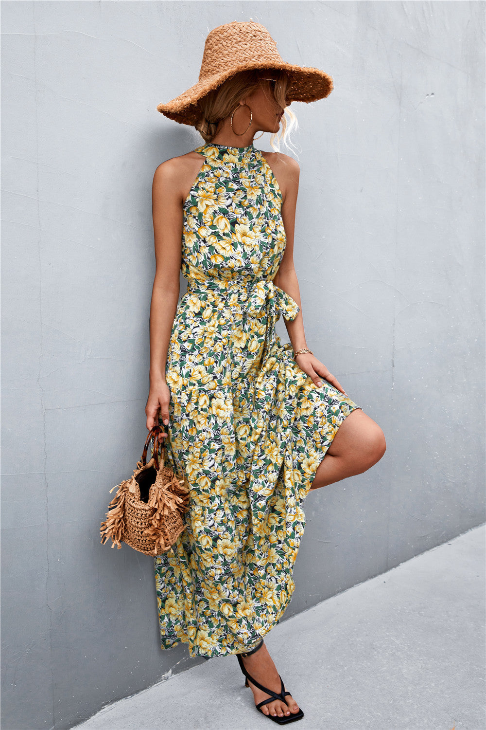 Yellow floral print maxi dress with halter neckline and tie waist, styled with a straw hat.
