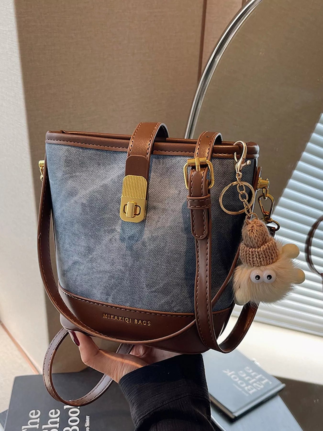 Bucket bag with brown trim, gold buckle, and fuzzy charm.