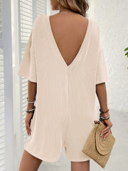 Blush pink ribbed knit romper with a plunging back and short sleeves.