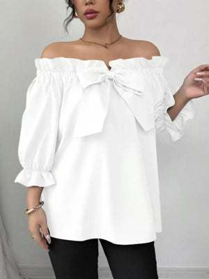 White off-the-shoulder blouse with ruffled neckline, bow detail, and puff sleeves.