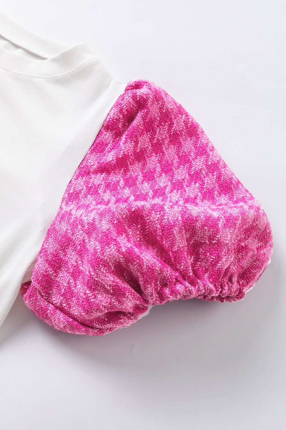 White ribbed knit blouse with pink houndstooth puff sleeves.