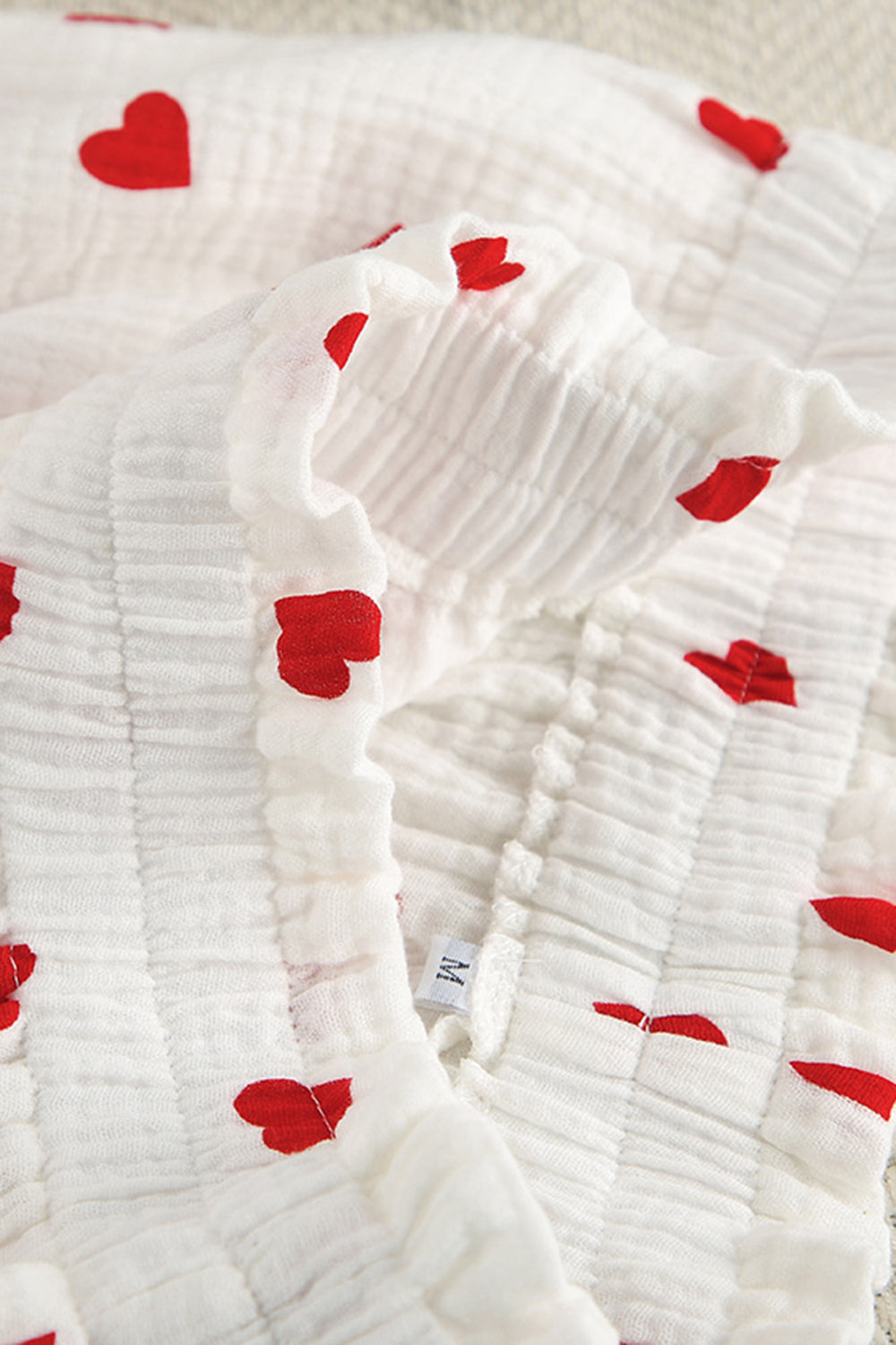 White gauze pajama top with red heart print and ruffled neckline detail.