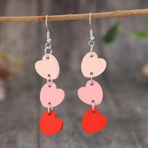 Cascading heart dangle earrings in blush pink and red wood with silver hooks.