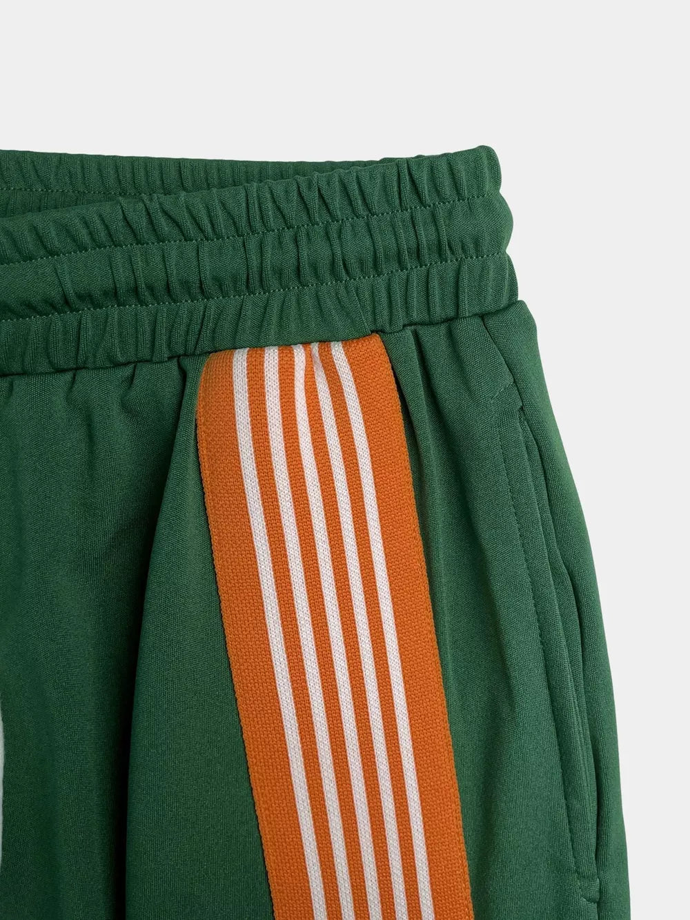Green athletic-chic two-piece set shorts with orange and white side stripes and elastic waistband.