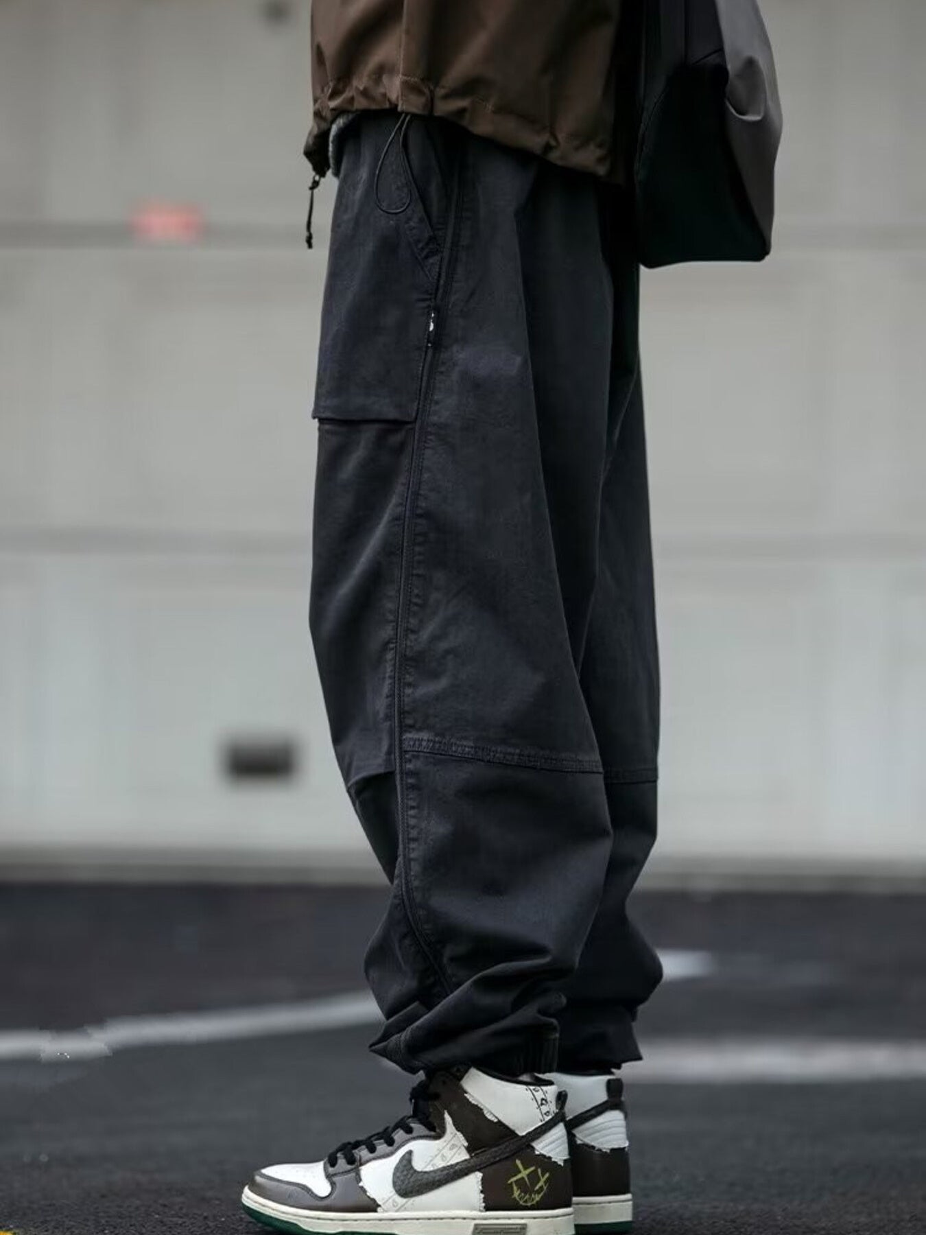 Men's black drawstring sweatpants with cargo pockets and zippered details.