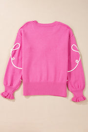 Fuchsia pink knit sweater with white embroidered bow motif on sleeves and ruffled cuffs.