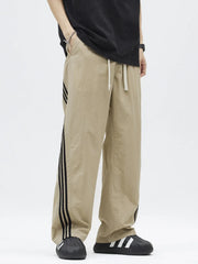 Khaki casual drawstring pants with black side stripes and loose fit.