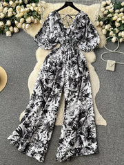 Tropical print smocked wide-leg romper with V-neck and puff sleeves.