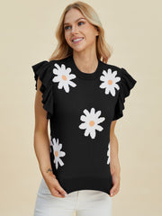 Black knit blouse with white daisy pattern and ruffled short sleeves.