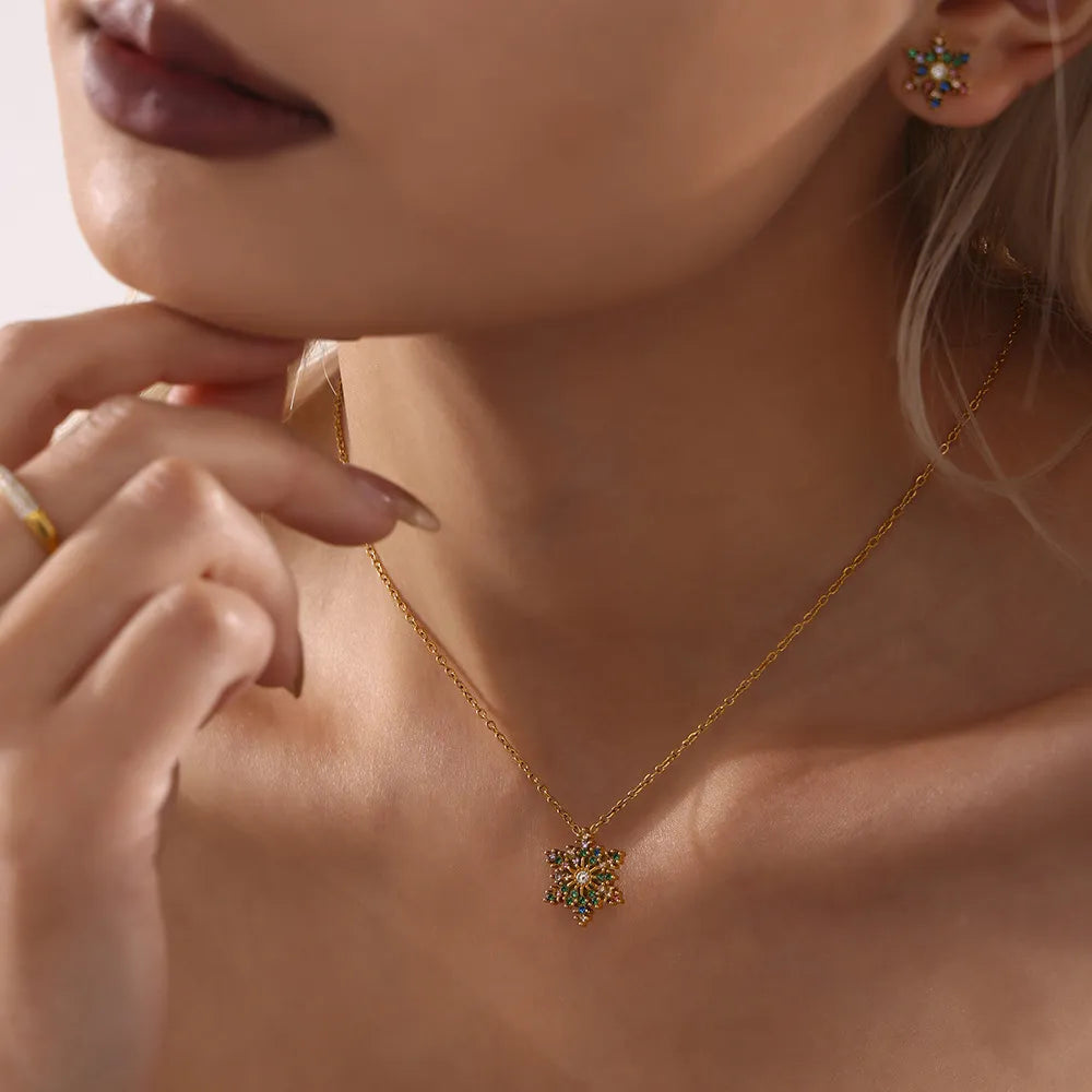 Celestial snowflake pendant necklace with colorful gems on a gold chain.