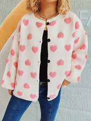 White acrylic button-down cardigan with textured pink heart motif and black buttons.