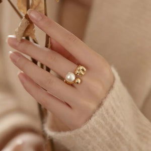 Lustrous pearl and gold open ring with textured details.