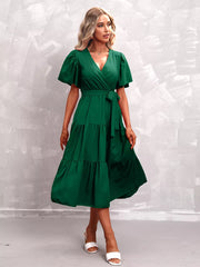 Dark green flutter sleeve tiered midi dress with wrap neckline and tie belt.