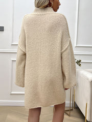 Beige knit mini dress with voluminous sleeves and a high neckline, shown from the back.
