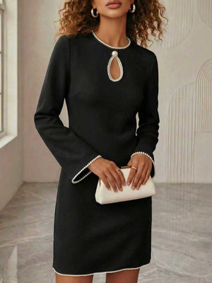Black mini dress with pearl trim and keyhole neckline, long sleeves.