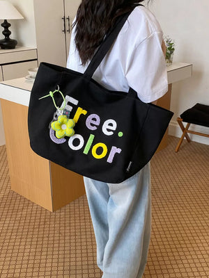 Black canvas shoulder bag with embroidered "Free. Color" text and flower charm