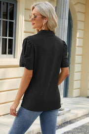 Black perforated polo top with ruched puff sleeves and a textured pattern.