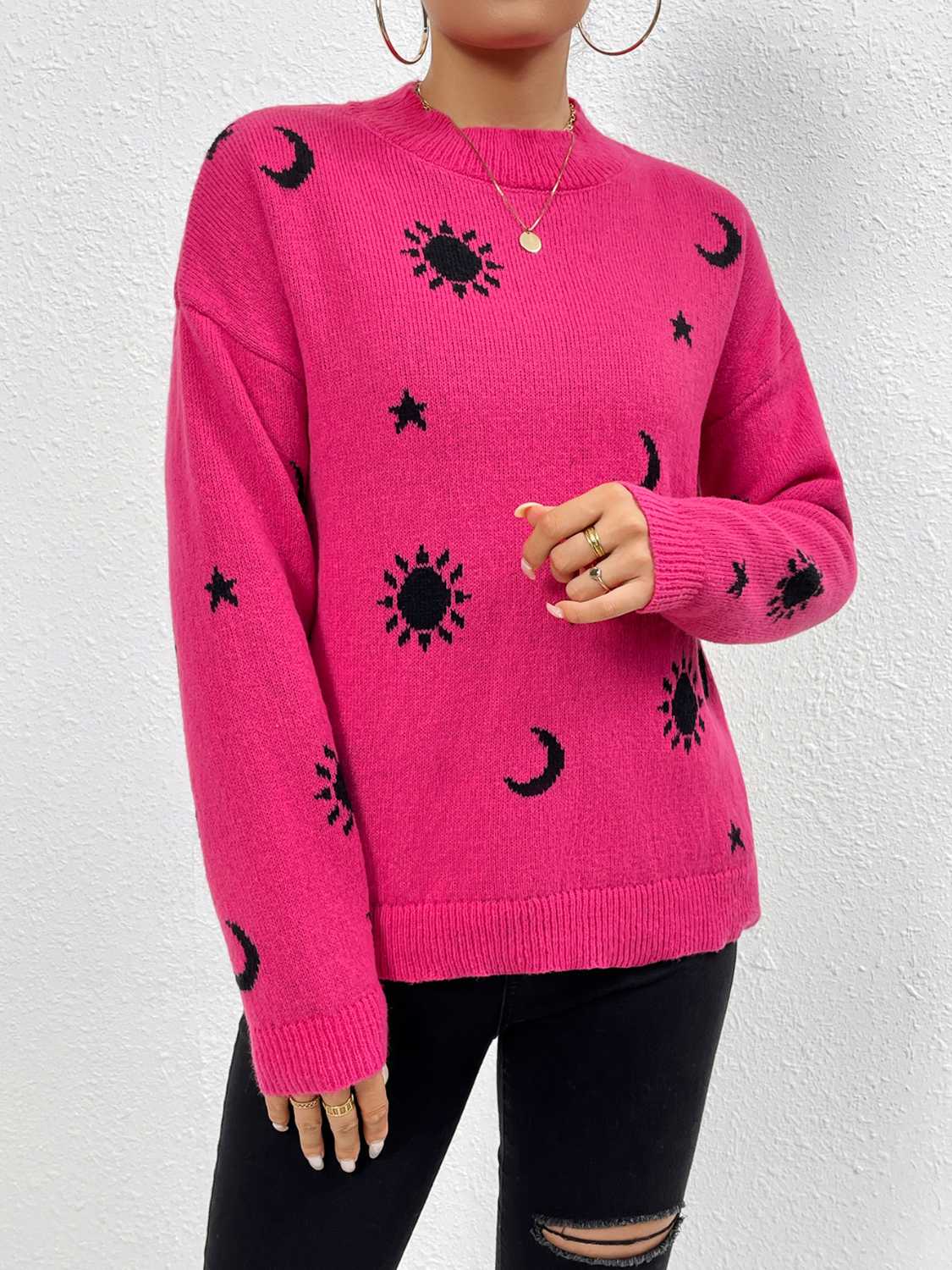 Hot pink knit sweater with black cosmic sun, moon, and star print, drop shoulder, crew neck.