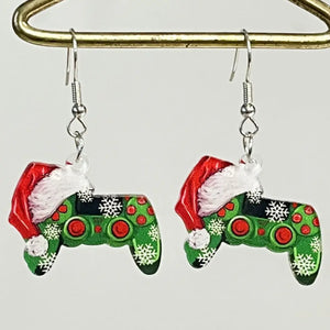 Festive acrylic drop earrings shaped like green game controllers with red buttons and snowflakes, wearing Santa hats.