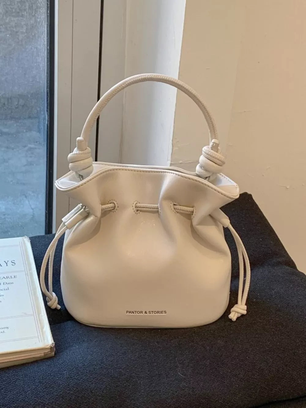 White pu leather cinch-top crossbody bag with knotted handle detail