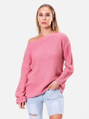 Off-shoulder waffle knit sweater in hot pink acrylic, with a slouchy fit and boat neckline.