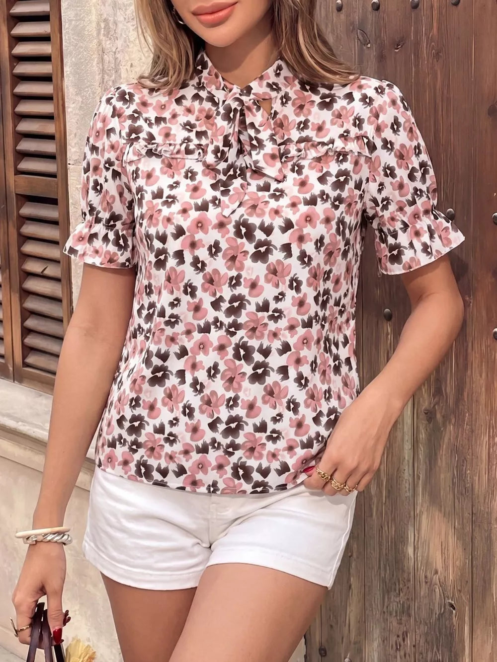 Floral tie-neck ruffle shirt with short sleeves and a ruffled collar.
