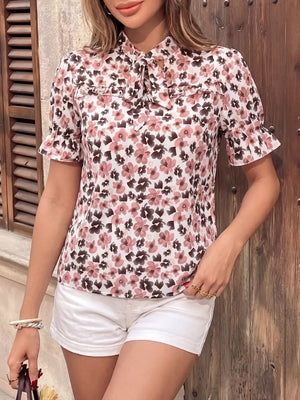 Floral tie-neck ruffle shirt with short sleeves and a ruffled collar.