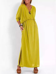 Yellow V-neck maxi dress with dolman sleeves, elastic waist, side slits, and pockets.