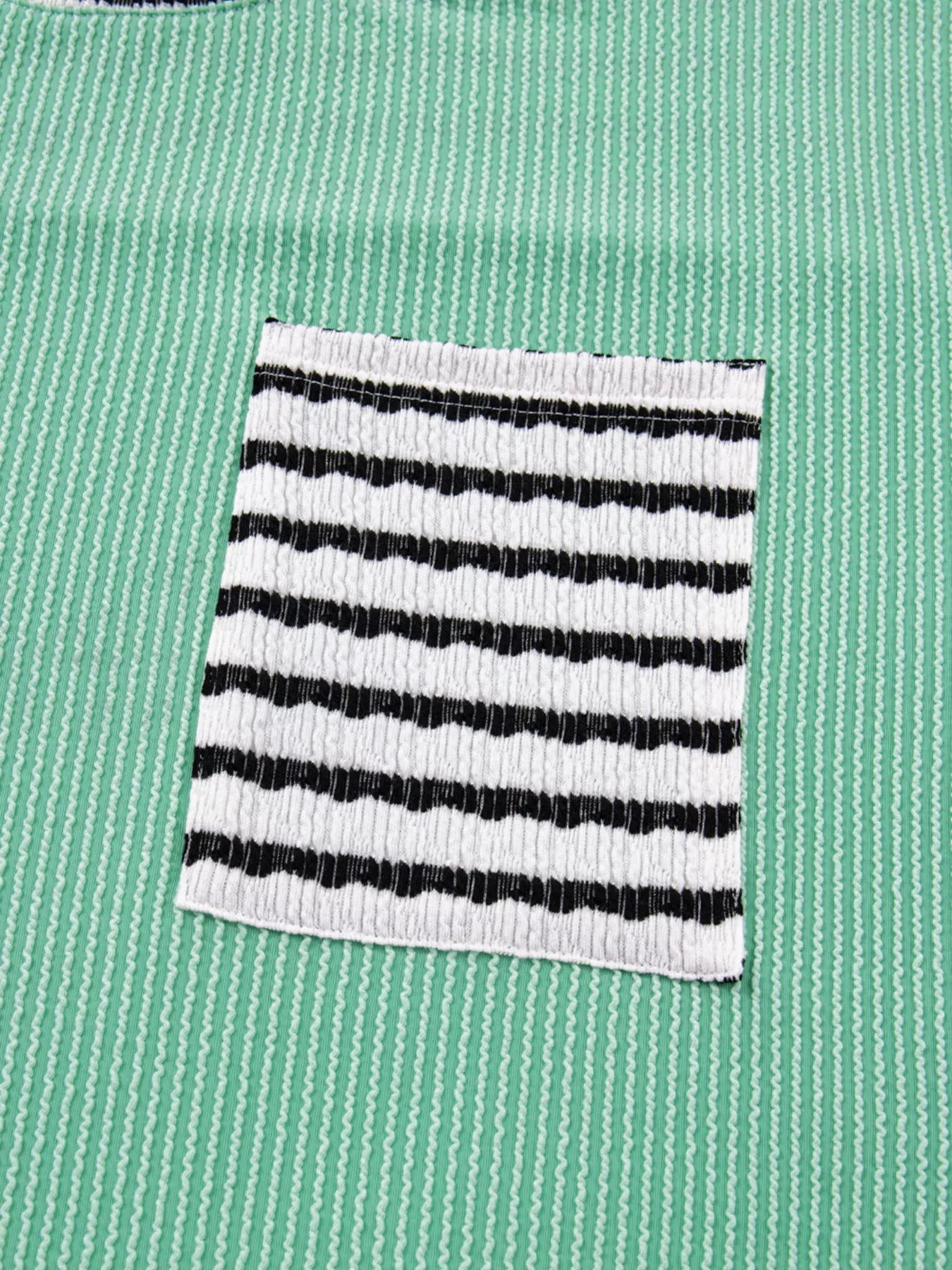 Turquoise long-sleeve top with twisted ribbing and a black and white striped pocket.