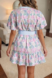 Floral mini dress with contrast trim, belted waist, puff sleeves, and ruffled hem.