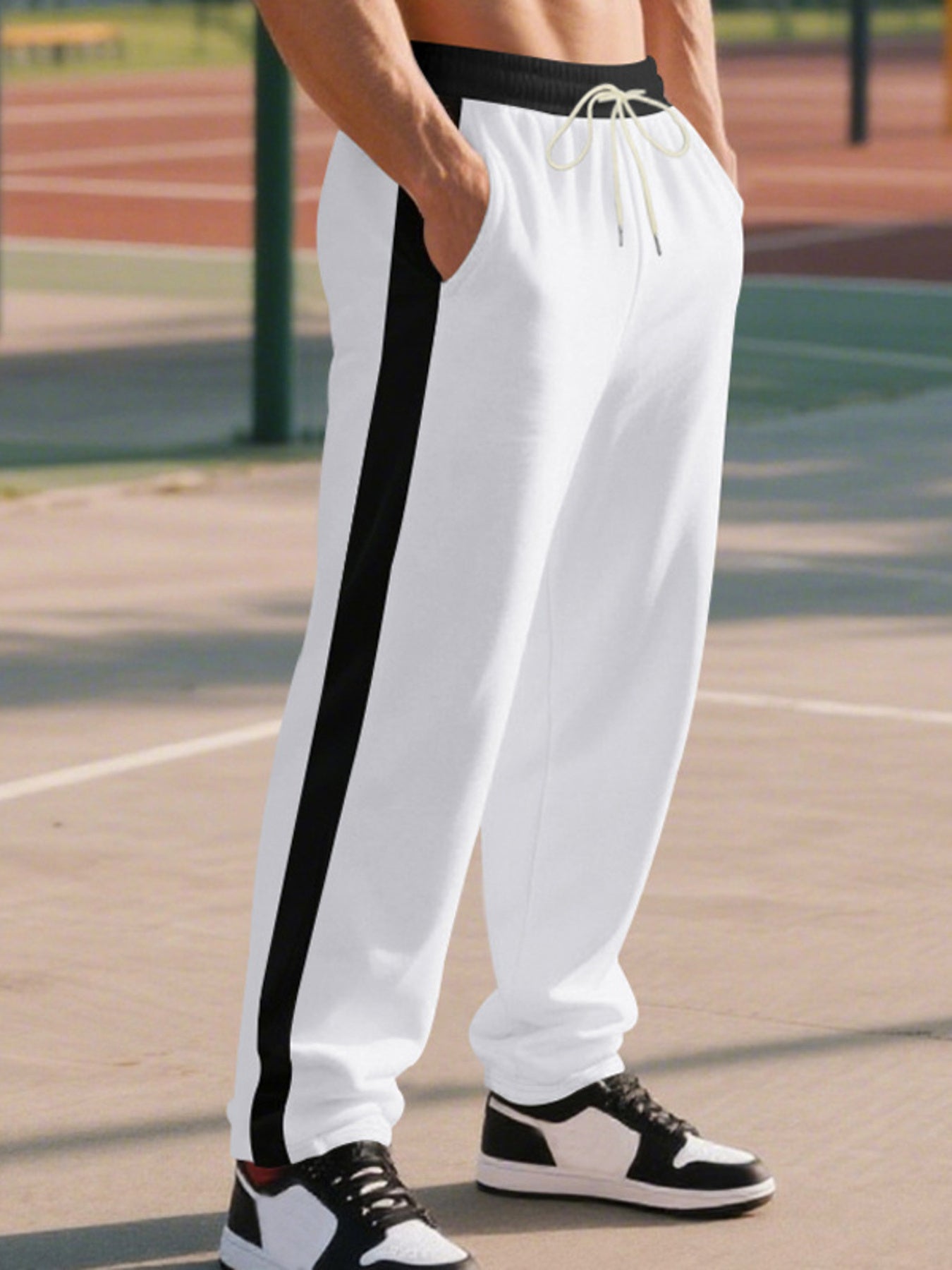 Men's white sweatpants with black side stripe and drawstring detail.