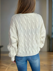 Oversized ivory cable knit turtleneck pullover sweater with textured knit detail.