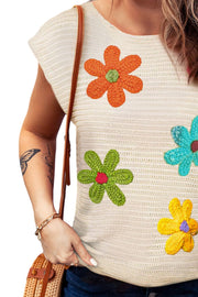 Cream knit top with colorful crochet floral appliqués and short sleeves.