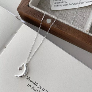 Sterling silver necklace with a crescent moon and star charm, delicate adjustable chain.
