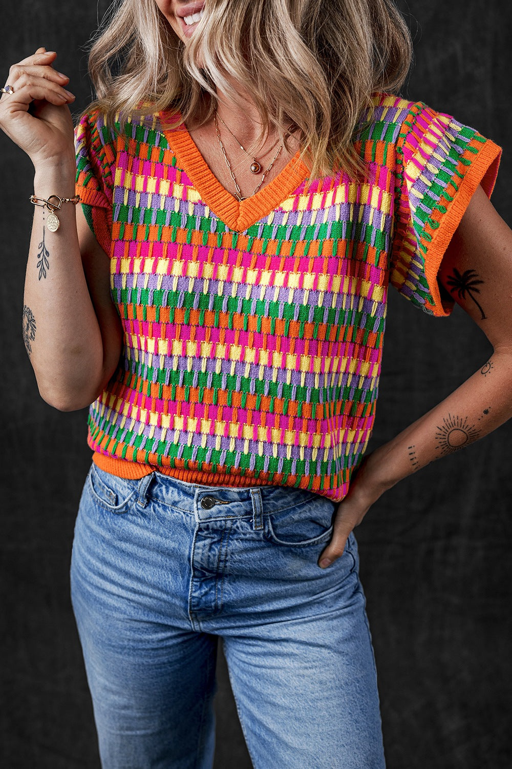 Geometric knit v-neck top in multicolor with flutter sleeves and orange trim.