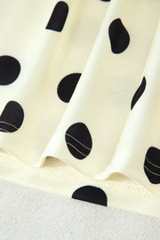 Cream polyester t-shirt with black polka dots and a high neckline detail.