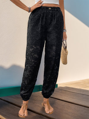 Black lace jogger trousers with elastic waist and cuffed ankles.