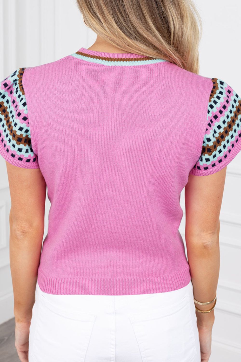 Fuchsia pink knit top with geometric patterned short sleeves and striped neckline.