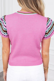 Fuchsia pink knit top with geometric patterned short sleeves and striped neckline.