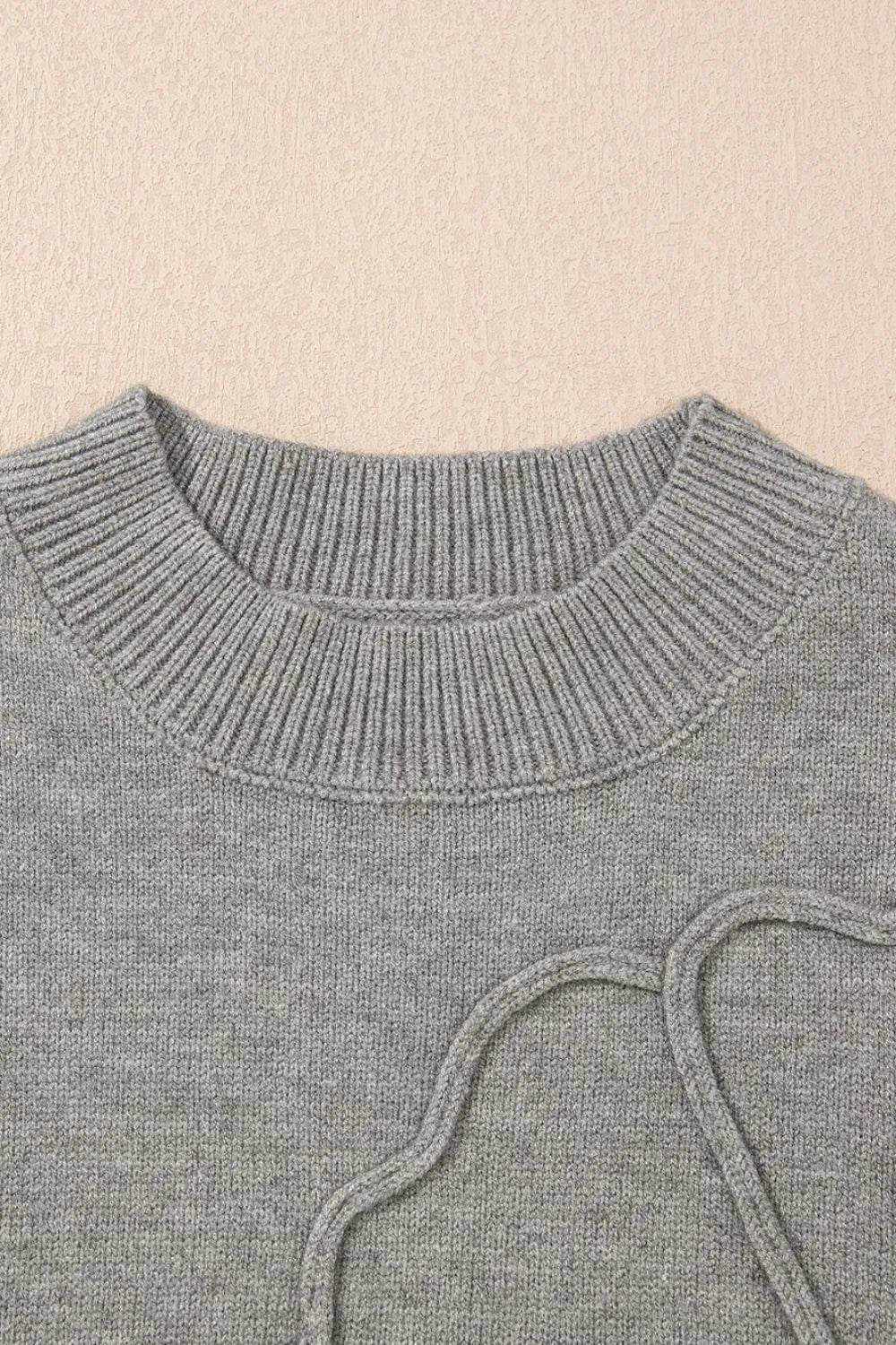 Gray knit top with a ribbed crewneck and drawstring detail.