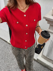 Red buttoned short-sleeve cardigan with V-neck and decorative pockets.