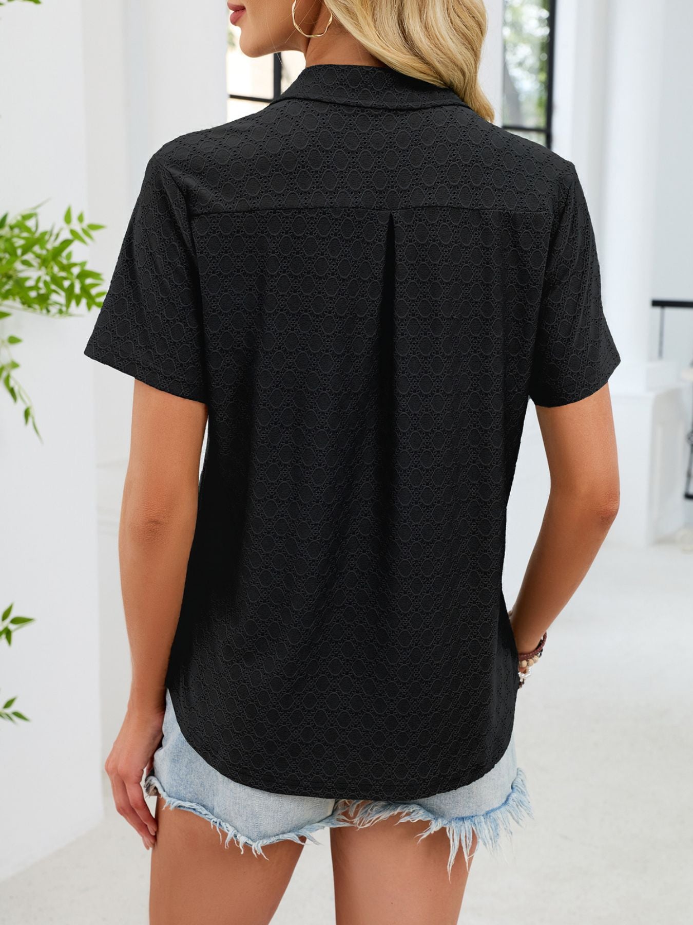 Black eyelet polo collar blouse with short sleeves and a relaxed fit.