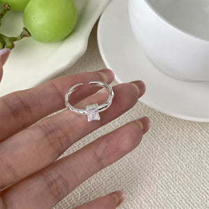 Sleek geometric zircon silver ring with a square cut stone on a textured band.