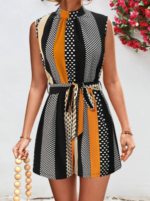 Black belted romper with polka dot and stripe patterns, mock neck, and sleeveless design.