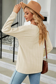 Cream textured cable-knit henley pullover with long sleeves and a crew neck.