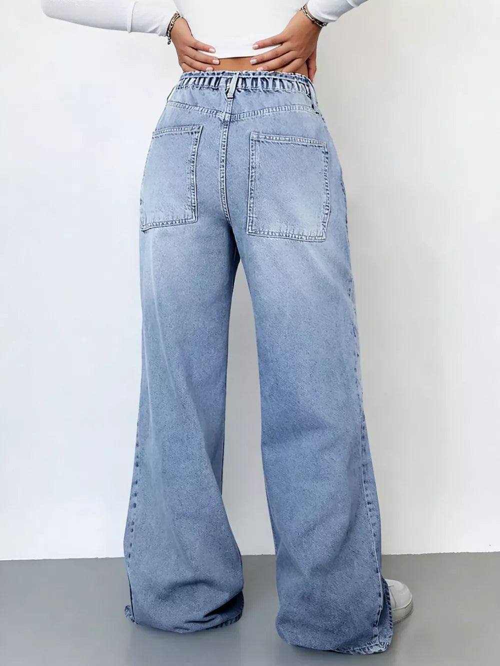 Light wash denim wide-leg cargo jeans with elastic waistband and large back pockets.