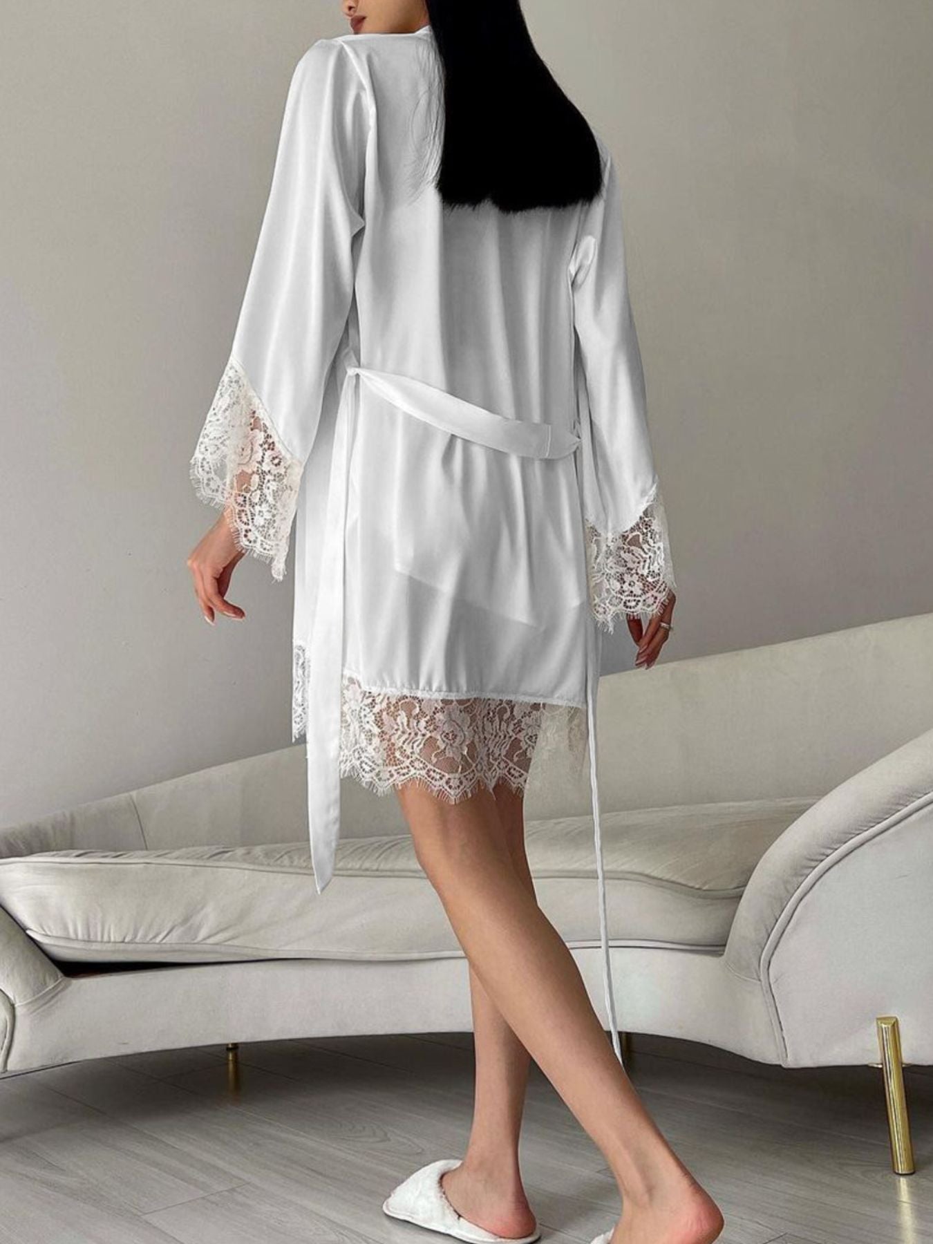 White satin robe with lace trim on sleeves and hem, tied with a sash.